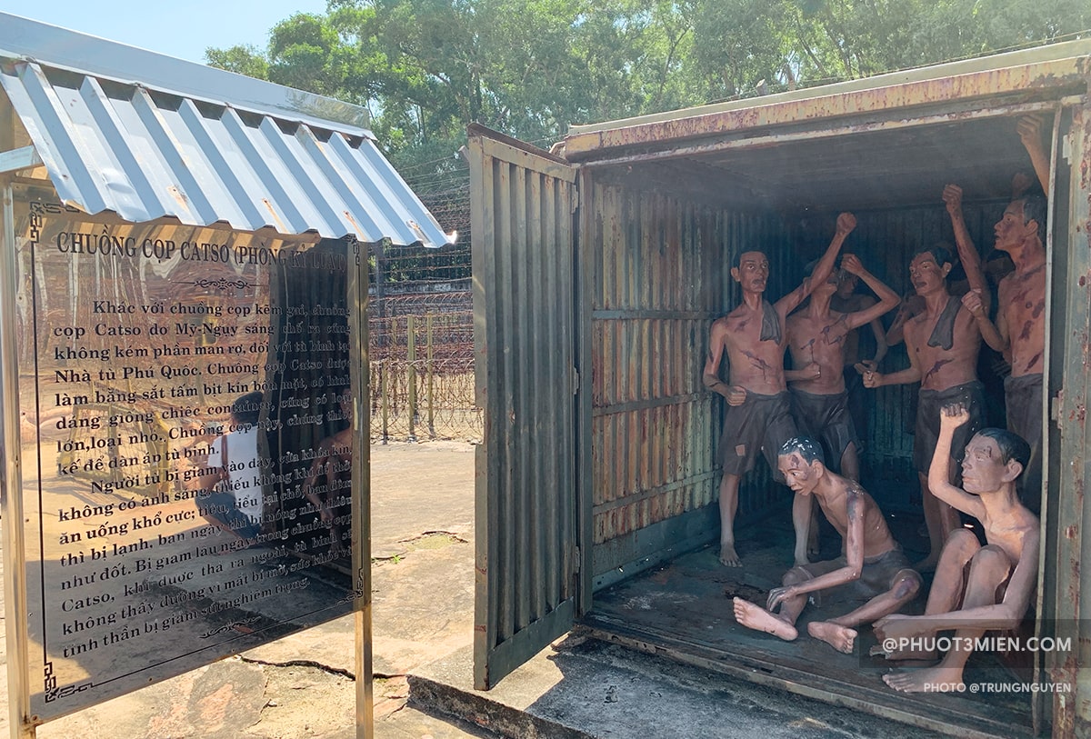 This image shows several prisoner figures inside a metal storage container. They are dirty and emaciated, yet with their arms raised in defiance.