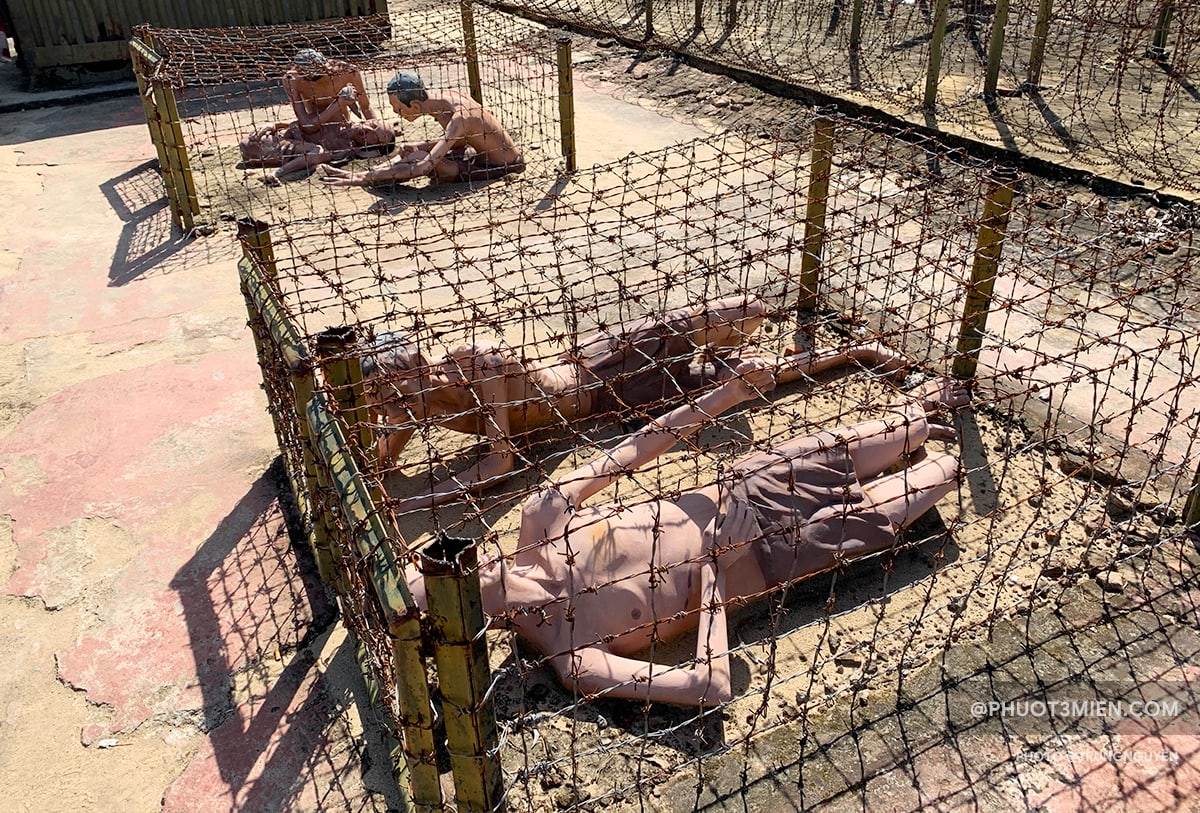 This image shows the "tiger cages" (small boxes of razor wire), with two fake prisoners sitting inside.